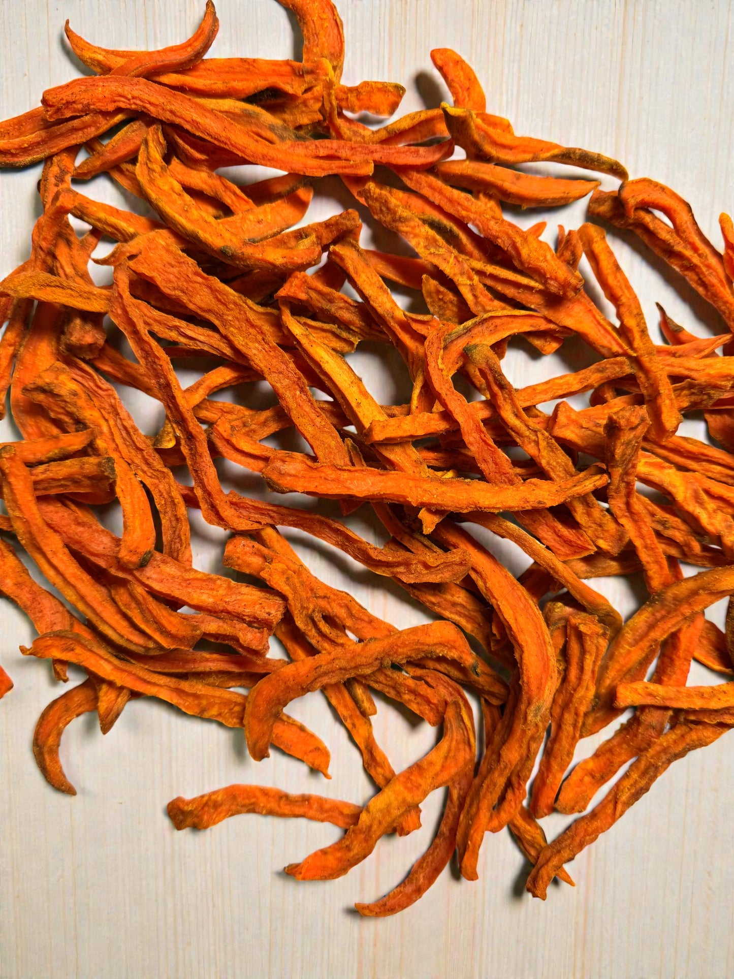 Dried orange vegetable strips on a light wooden surface. sweet potato fries for dogs